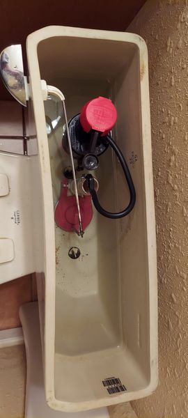 The inside of a toilet tank with a red cap on it.
