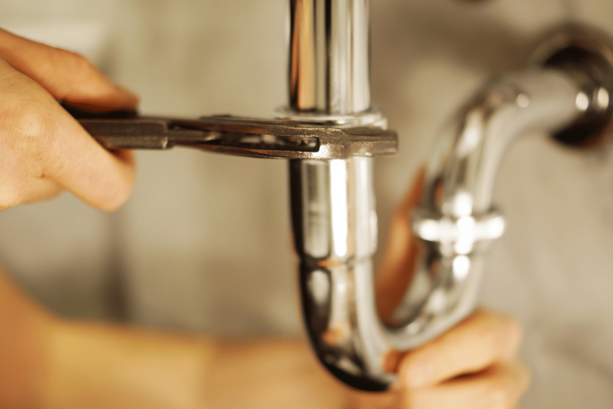 A person is fixing a pipe with a wrench