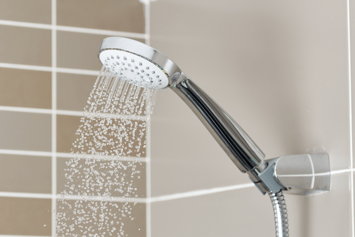 A shower head is spraying water in a bathroom