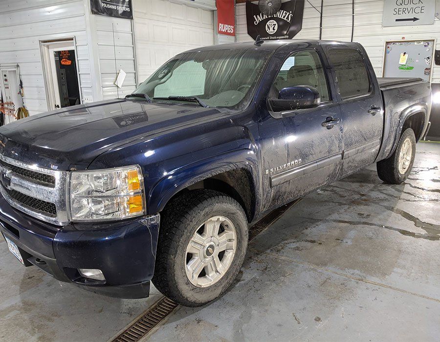 A blue pickup truck is parked in a garage.