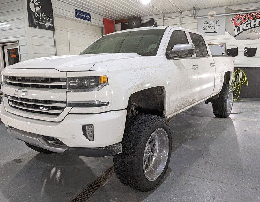 A white pickup truck is parked in a garage.