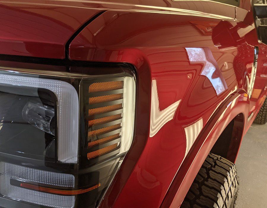 A red truck is parked in a garage with the hood up