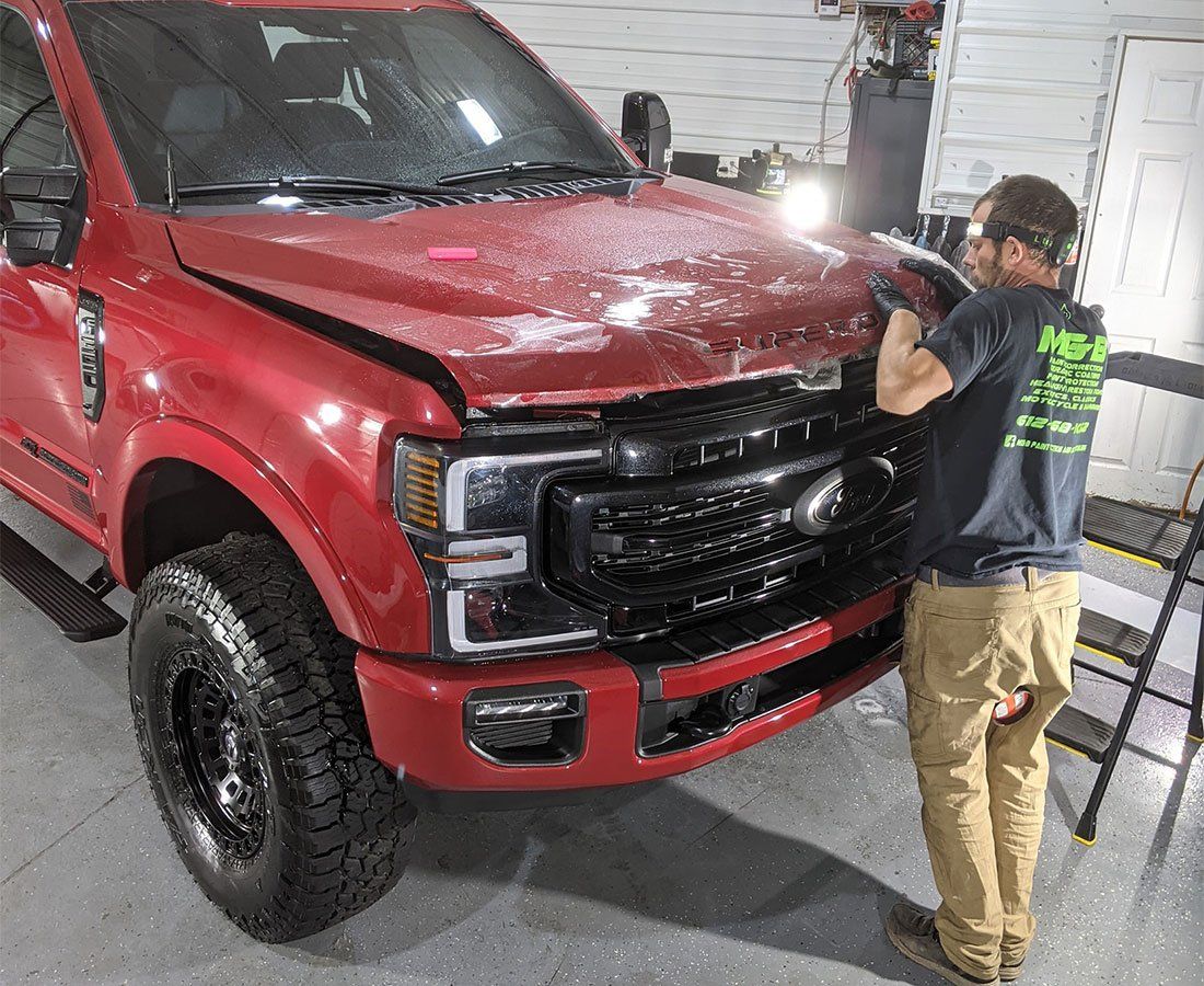 A man is standing next to a red truck in a garage.