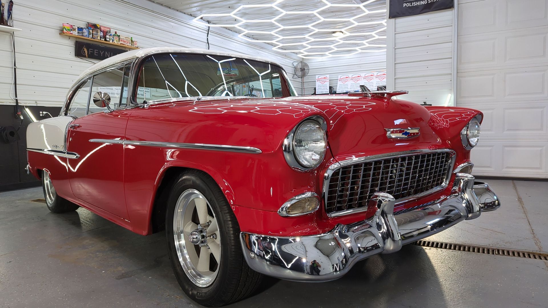 A red and white classic car is parked in a garage.