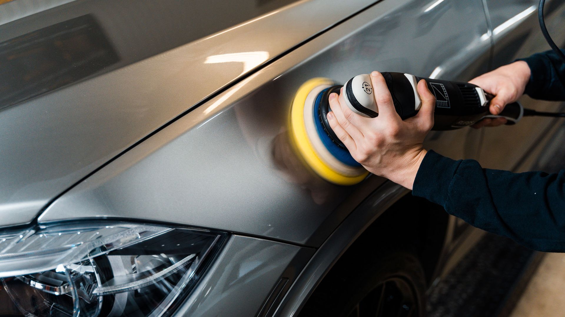 A person is polishing a car with a polisher.