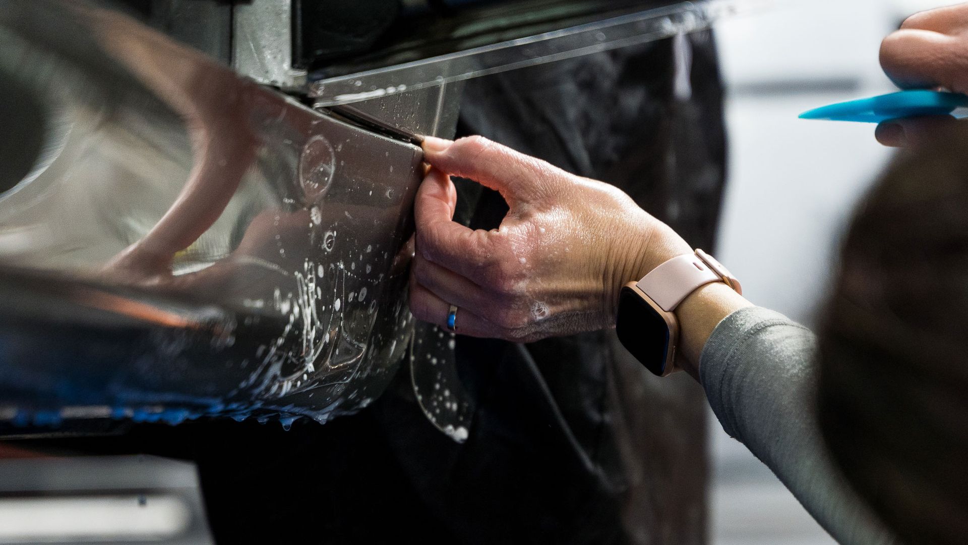 A person is applying plastic wrap to a car.