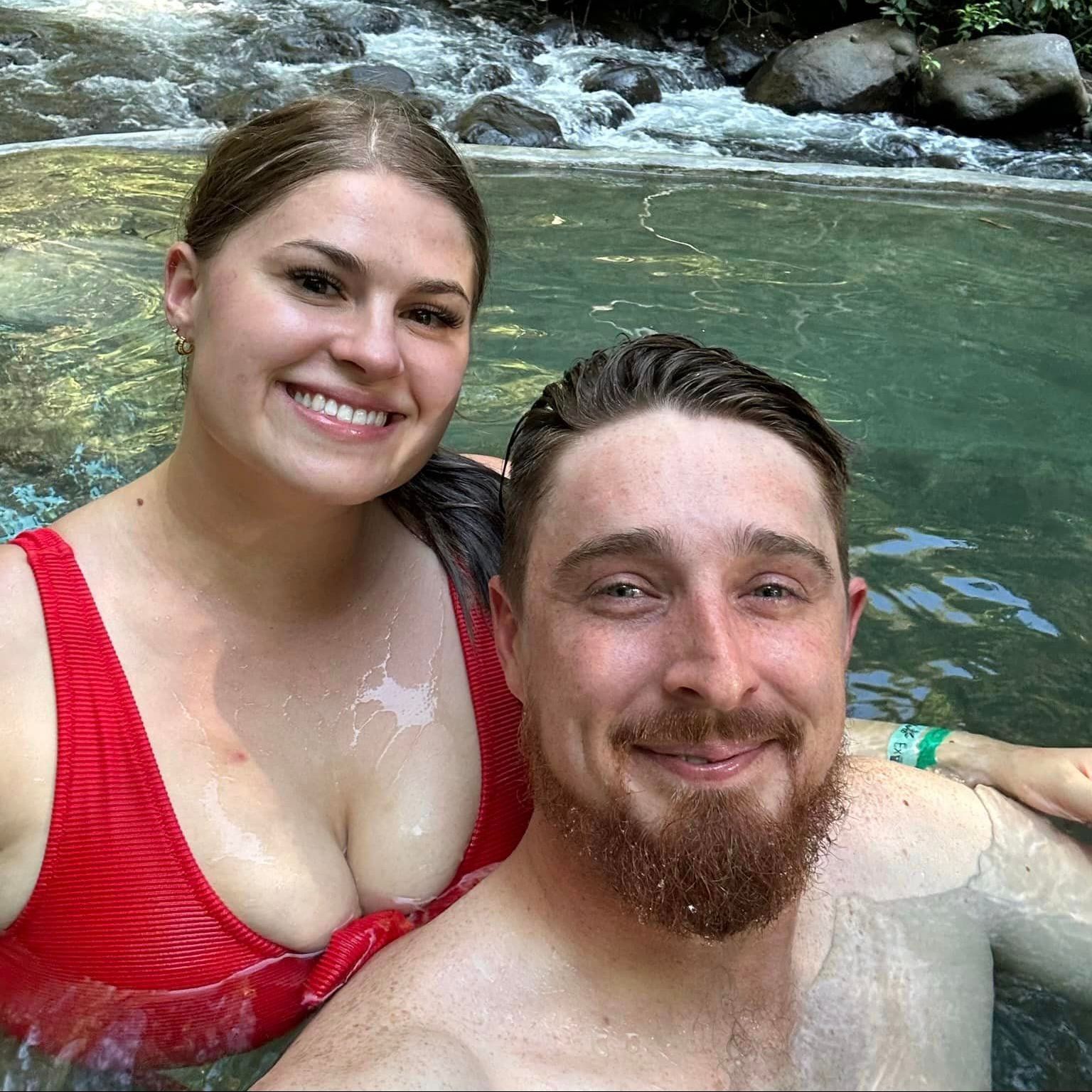A man and a woman are taking a selfie in a pool.