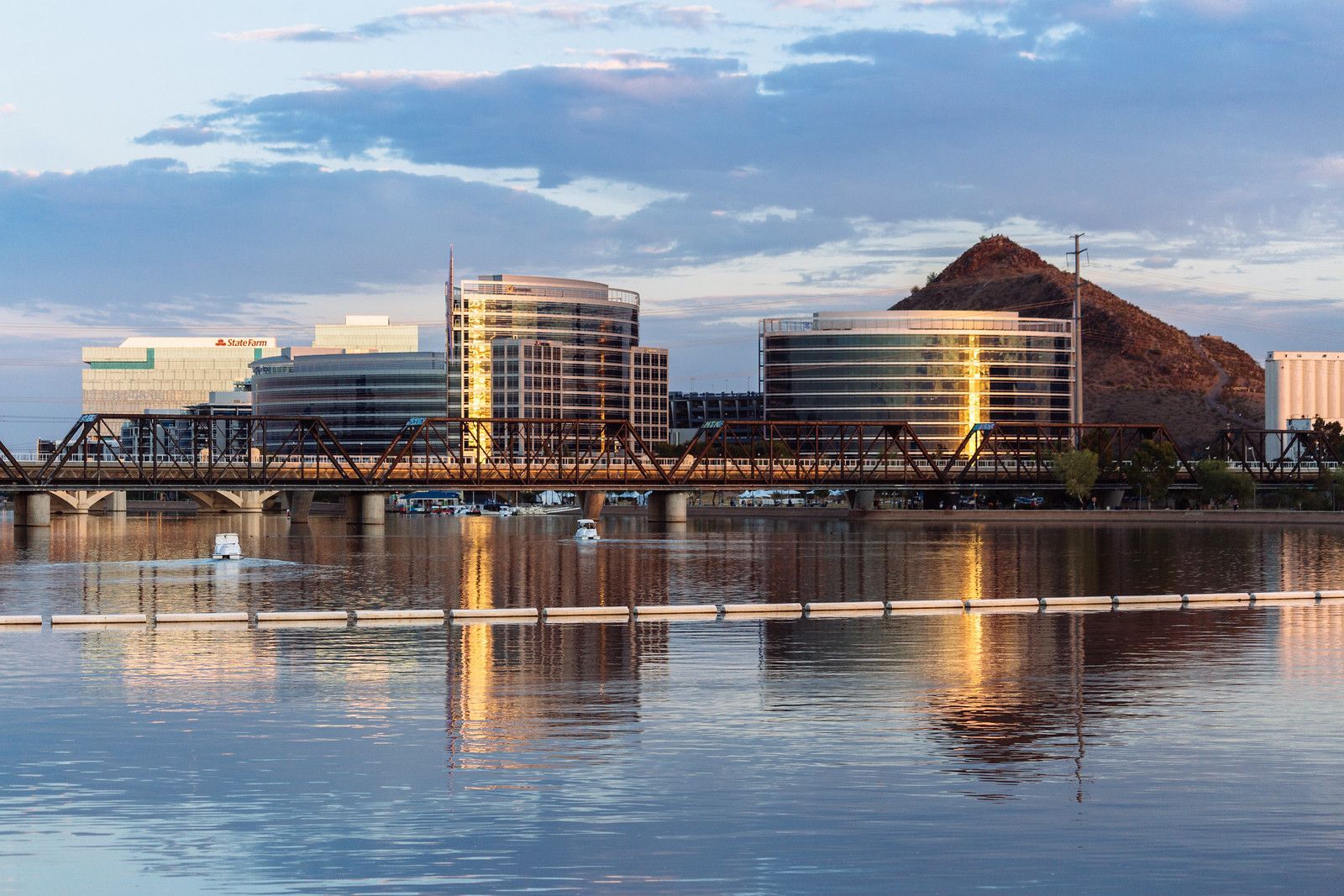 A city skyline is reflected in the water of a lake.
