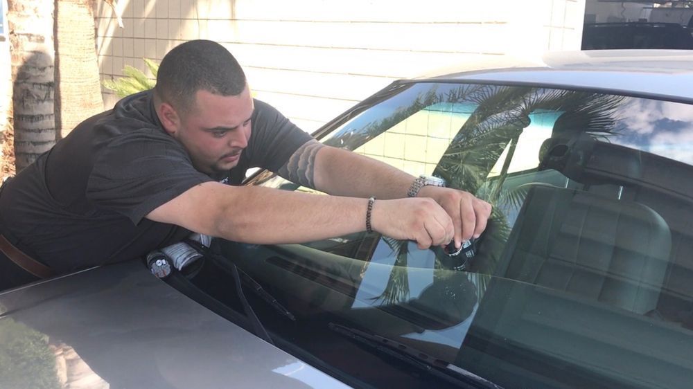 A man is repairing the windshield of a car.