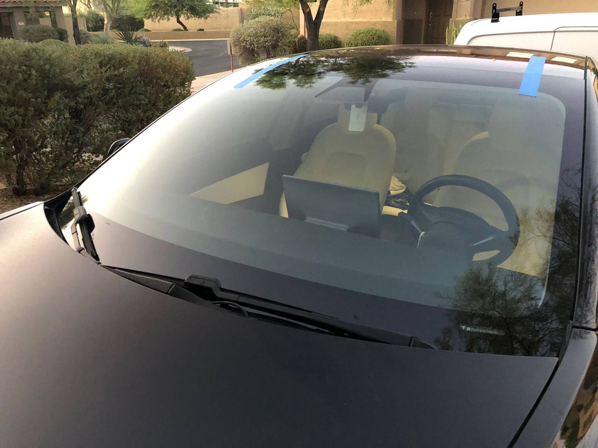 A close up of a car windshield with a steering wheel.