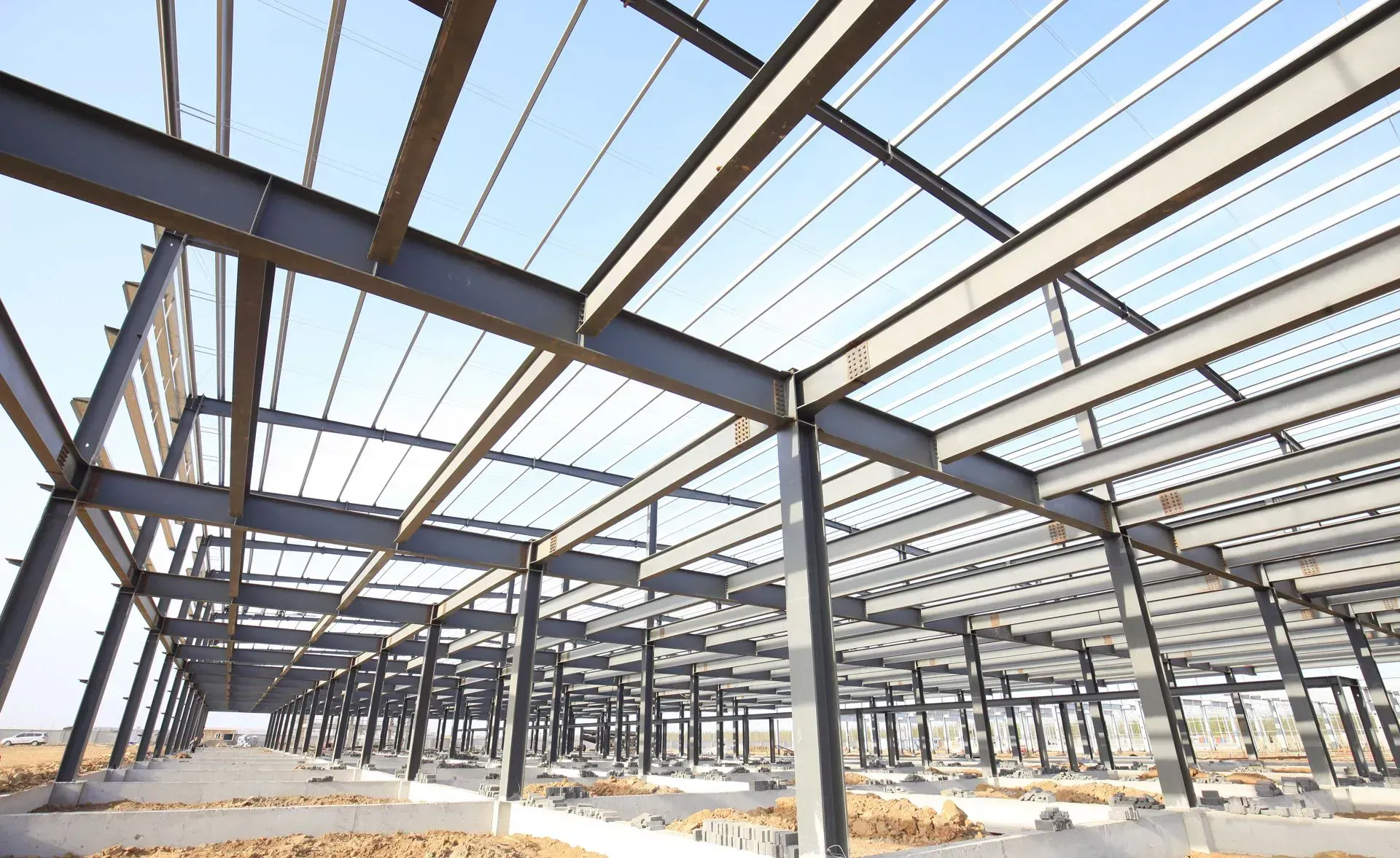 A large metal structure is under construction with a blue sky in the background.