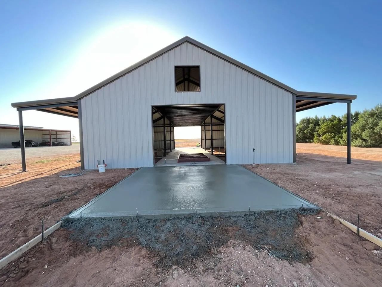 A white barn with a concrete driveway in front of it