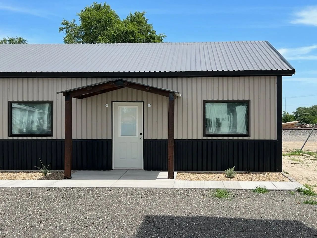 A small house with a porch and a gray roof