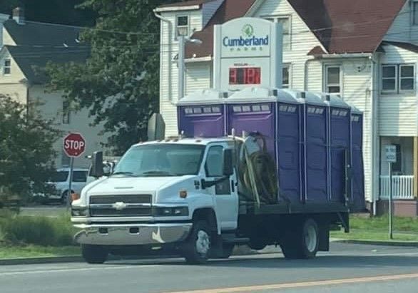 a white truck with purple portable toilets on the back of it