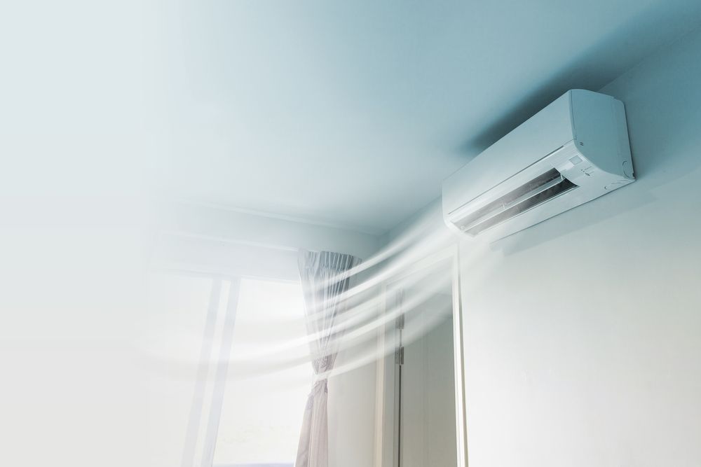 White Air Conditioner Mounted on Light Blue Wall With Air Flowing Out — Craig Stewart Electrical in East Wagga Wagga, NSW