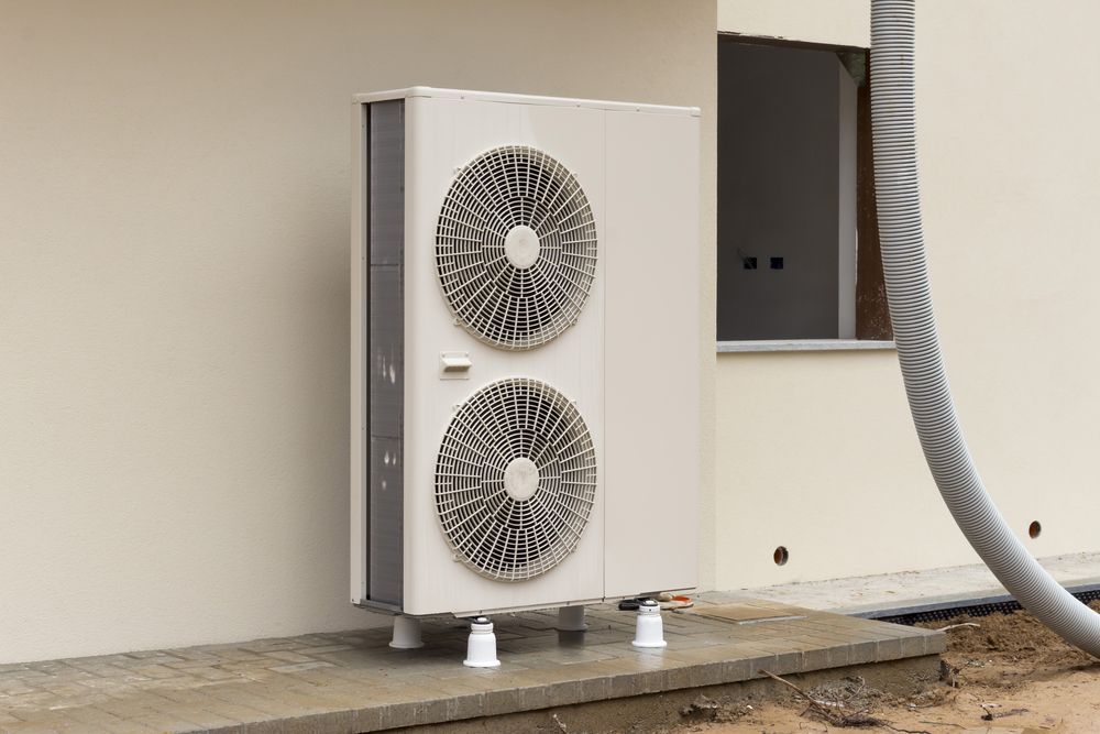 Air Source Heat Pump Mounted on Concrete Pad Next to a Building — Craig Stewart Electrical in East Wagga Wagga, NSW