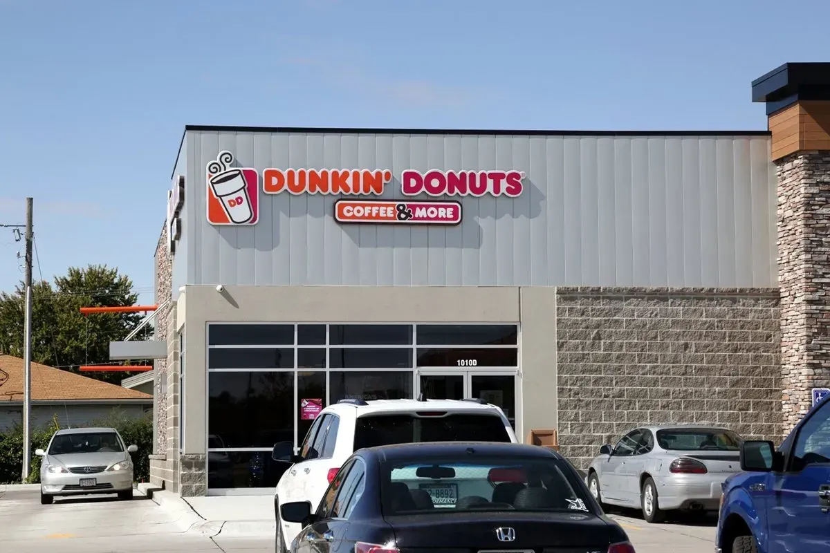 A dunkin donuts store with cars parked in front of it