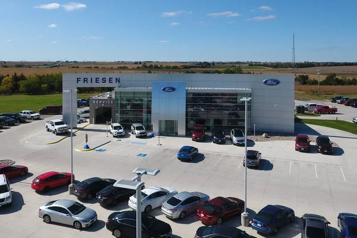 An aerial view of a ford dealership with a lot of cars parked in front of it.