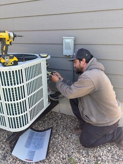A man is working on an air conditioner outside of a house