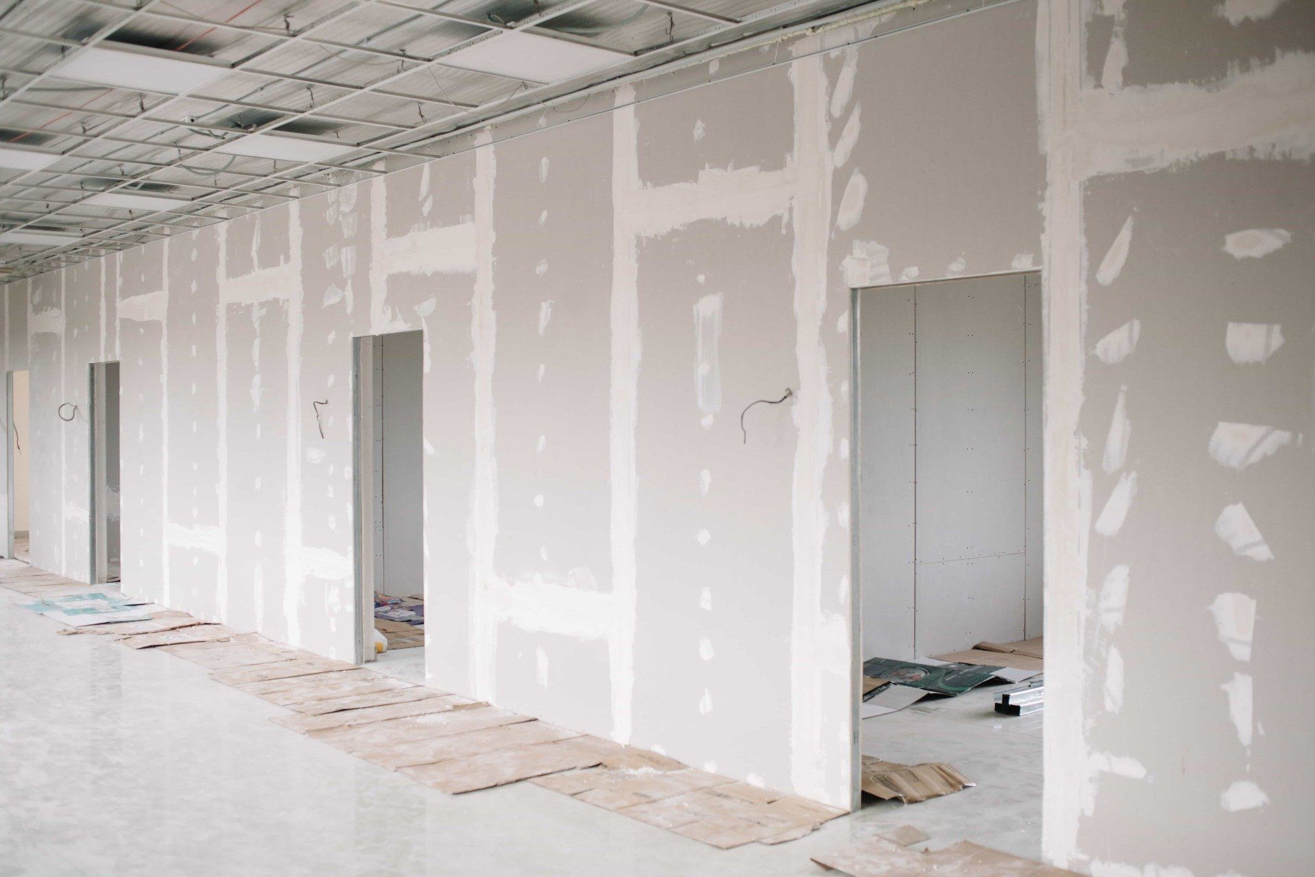 A long hallway with drywall walls and doors in a building under construction.