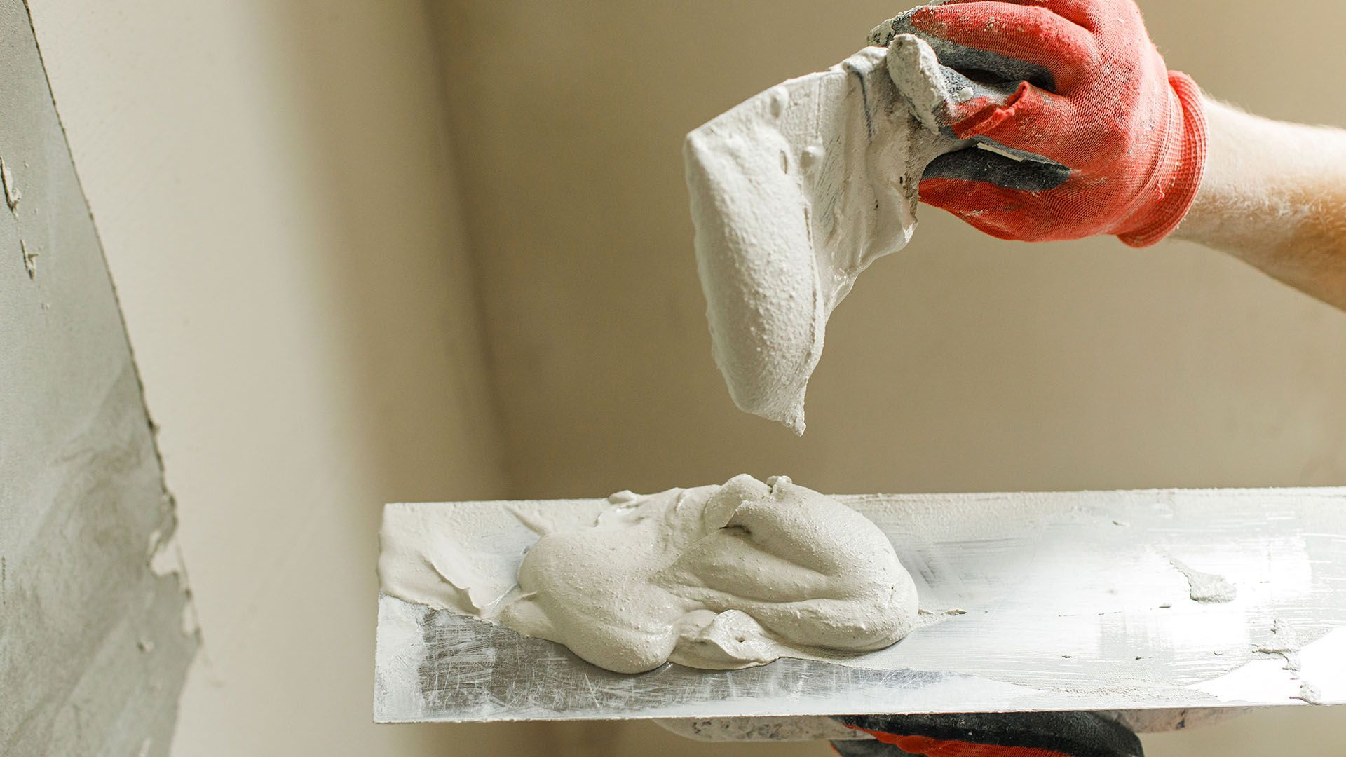 A person is plastering a wall with a trowel.