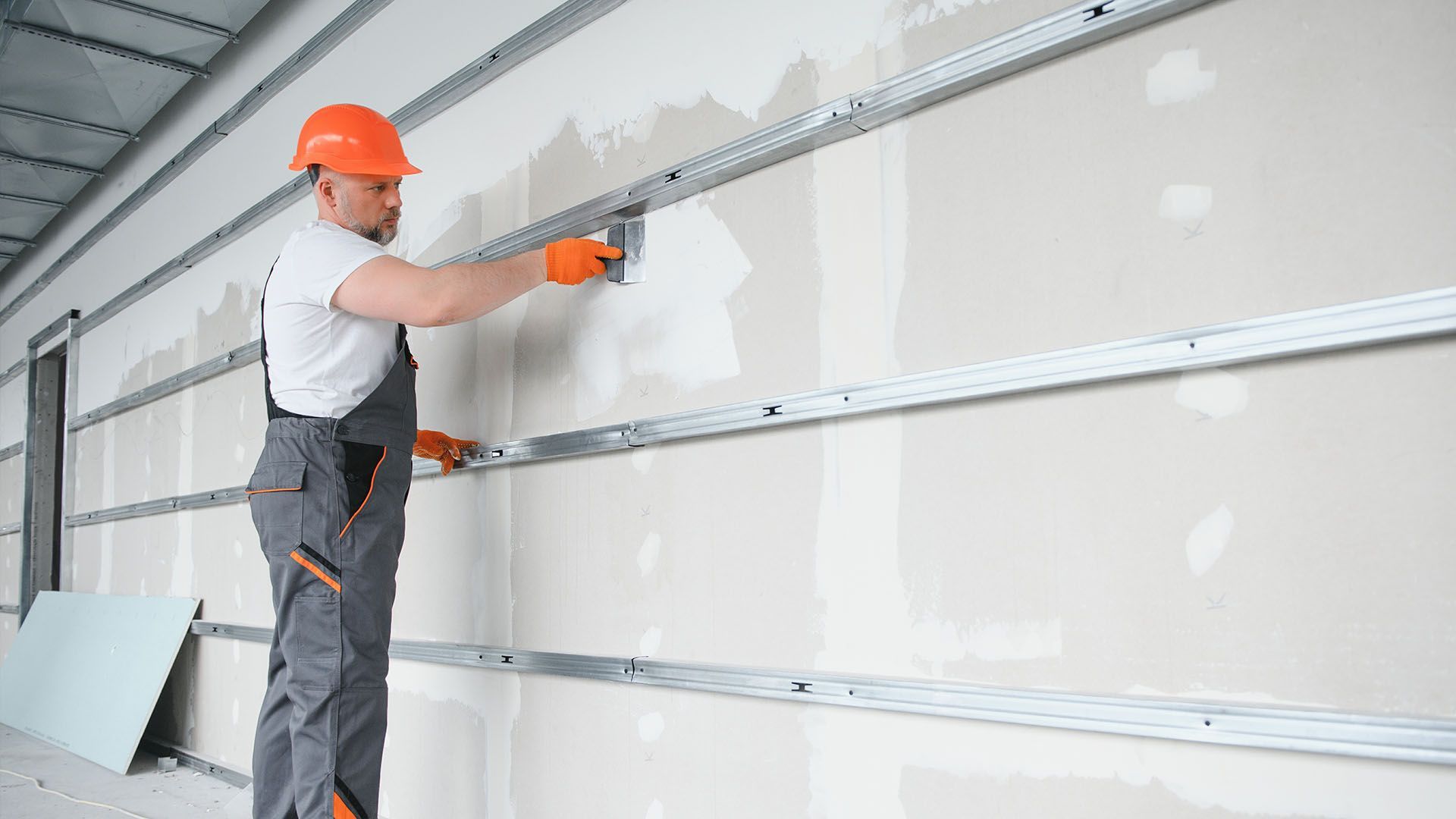 A man is measuring a wall with a tape measure.