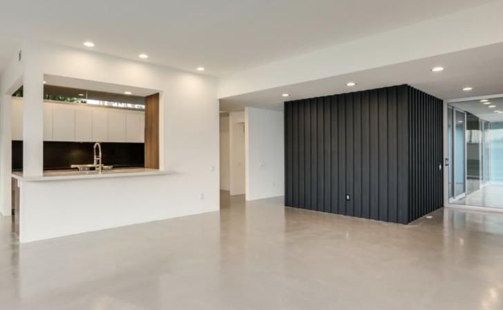 an empty living room with a kitchen in the background .