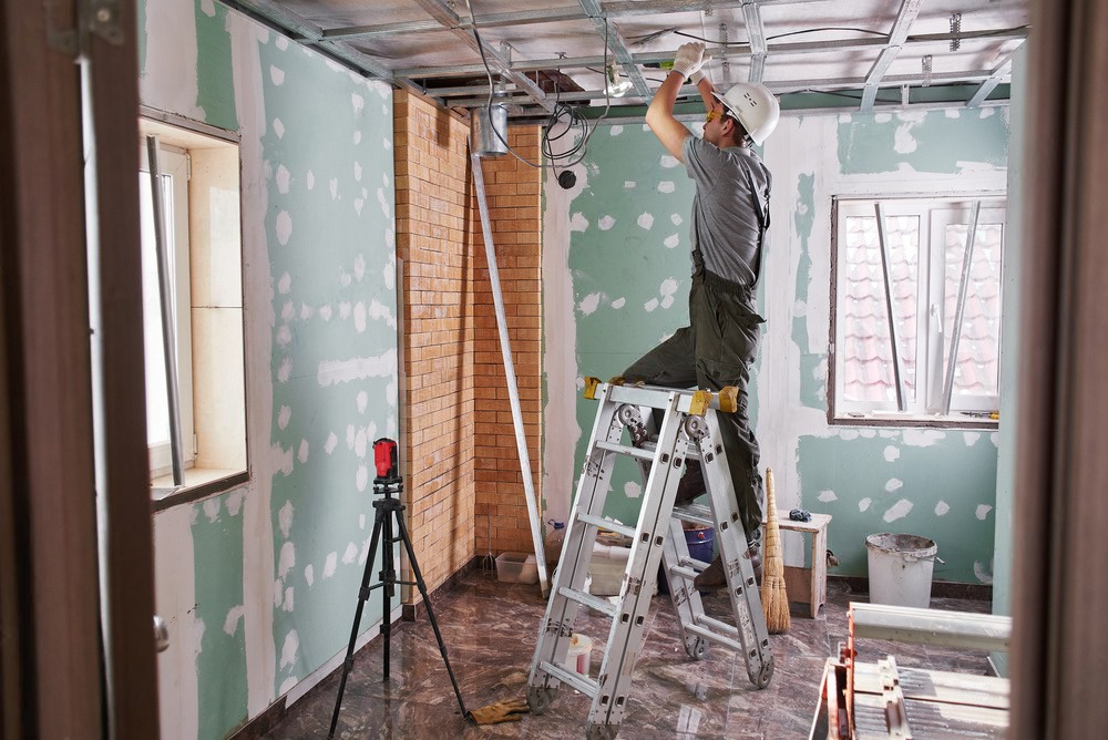 a man is standing on a ladder in a room under construction .