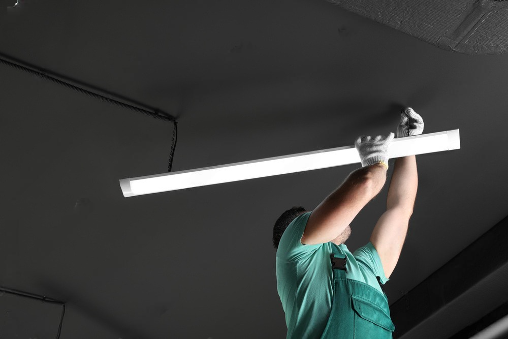 a man is hanging a light from the ceiling .