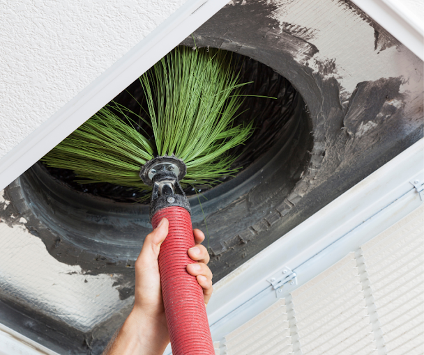 A person is using a brush to clean an air vent