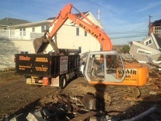 Trash Cleanout — Excavator Putting Junk On Dumpster in Middletown, NJ