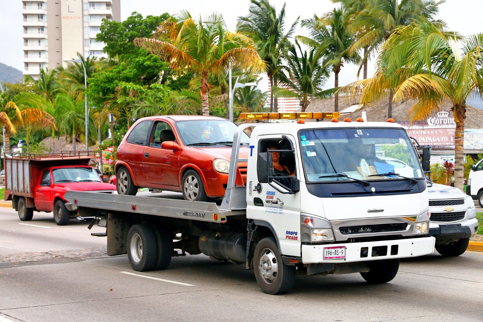 A tow truck with a red car on the back of it