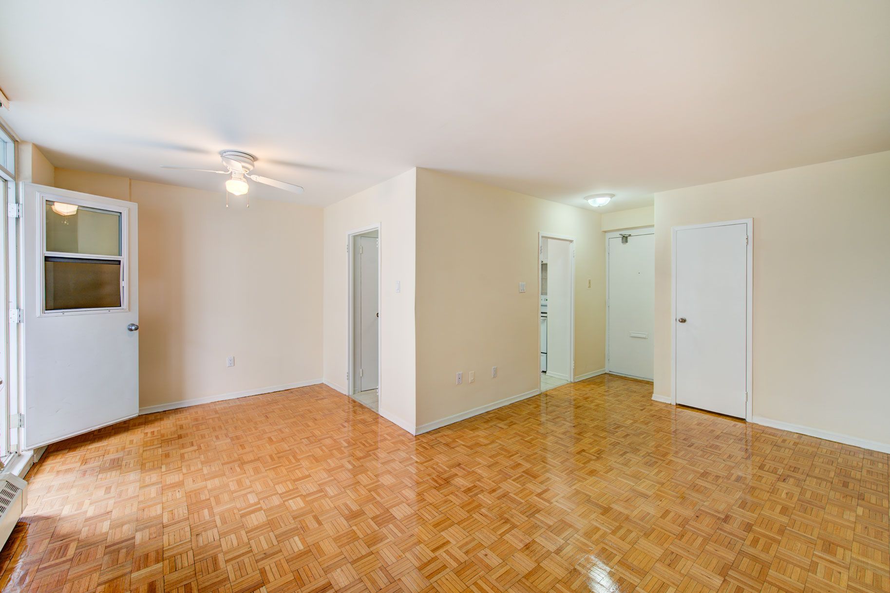 An empty living room with hardwood floors and a ceiling fan.