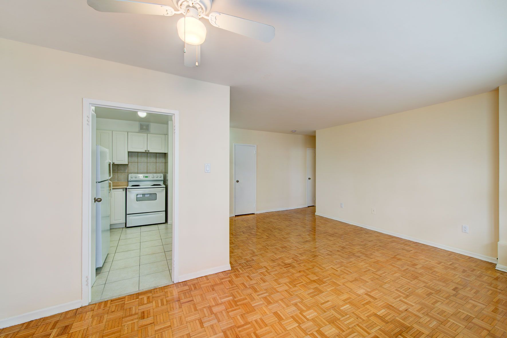 An empty living room with hardwood floors and a ceiling fan.