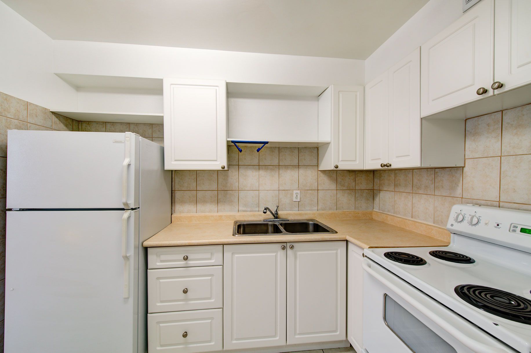 A kitchen with white cabinets , a stove and a refrigerator