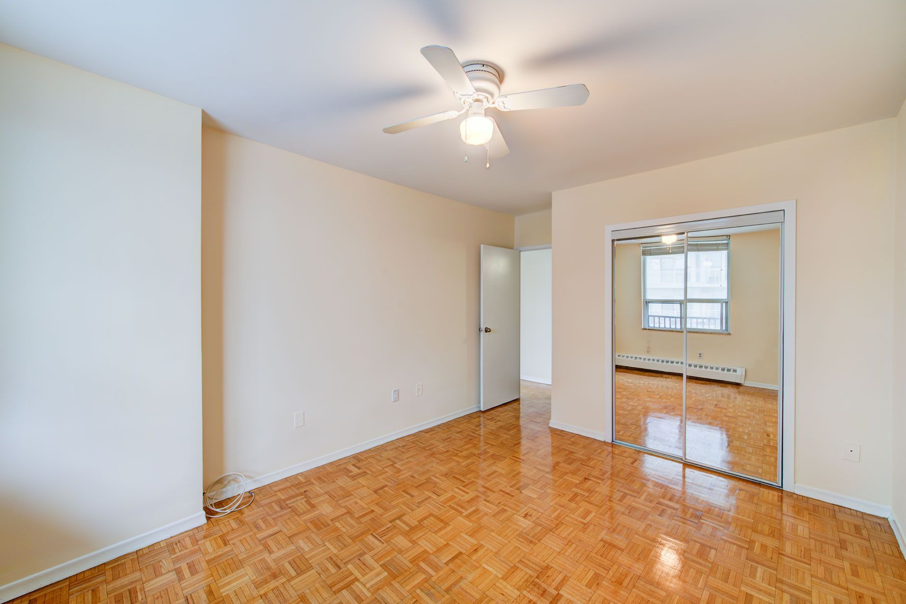 An empty room with a ceiling fan and mirrors