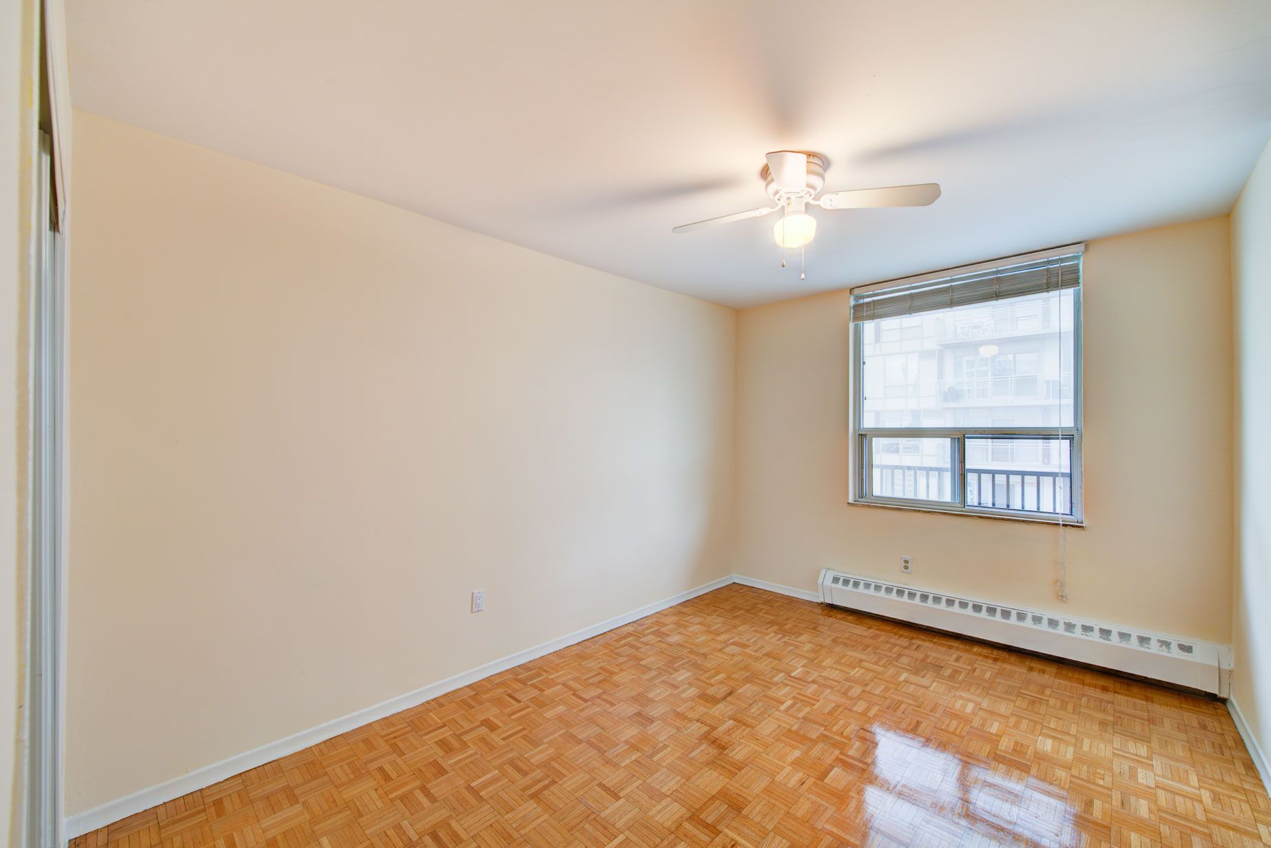 An empty room with a ceiling fan and a window.