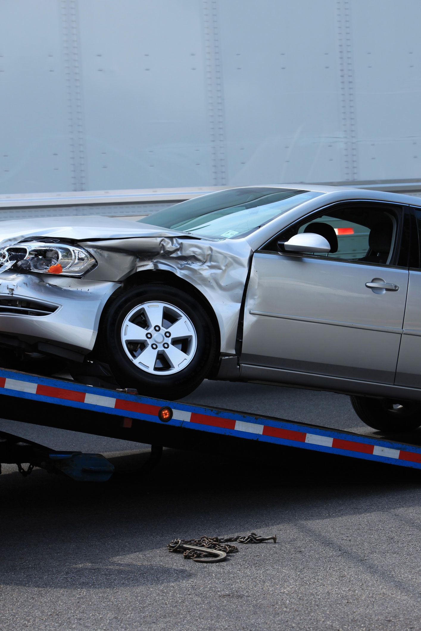 A damaged car is being towed by a tow truck.