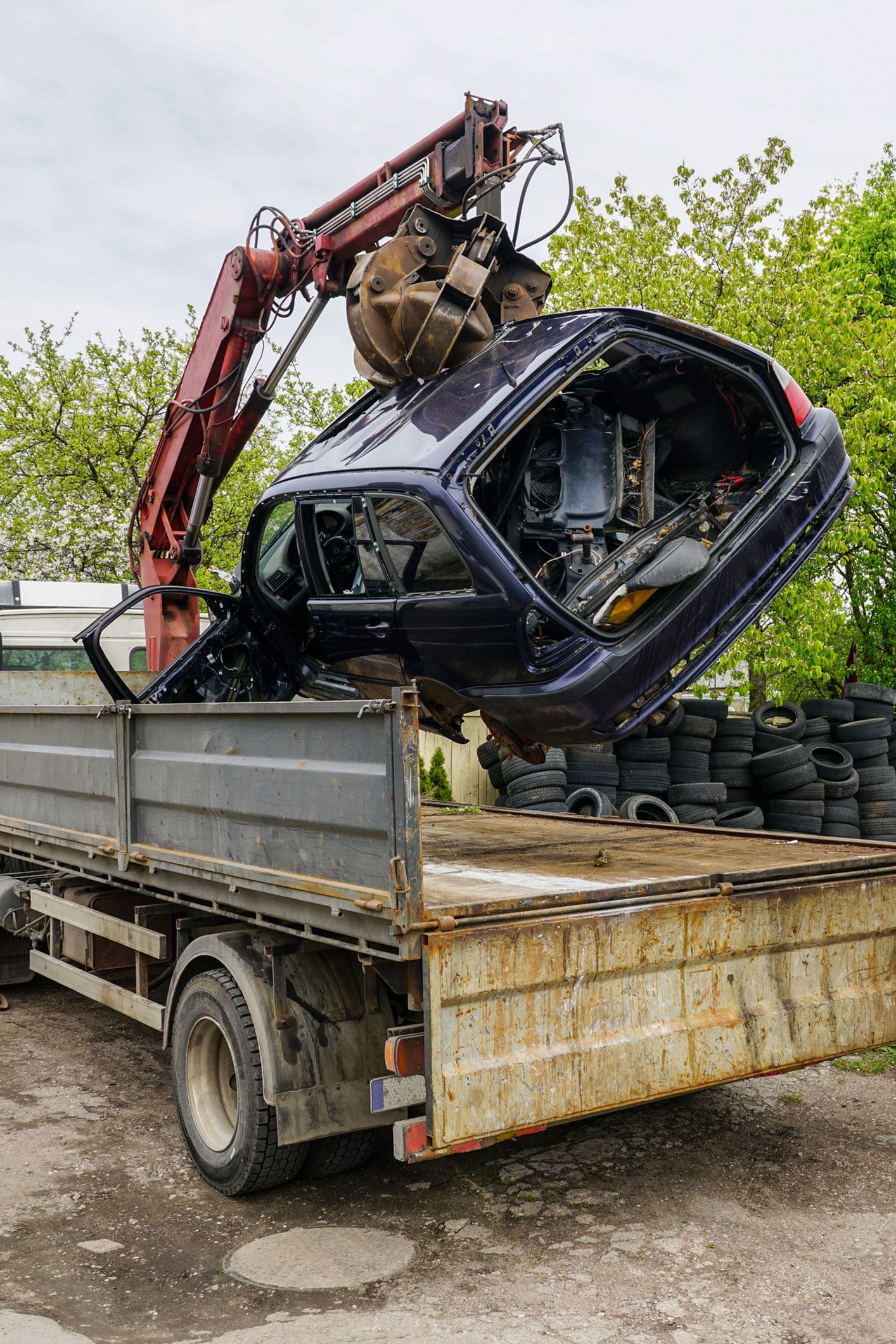 A crane is lifting a car from the back of a truck.