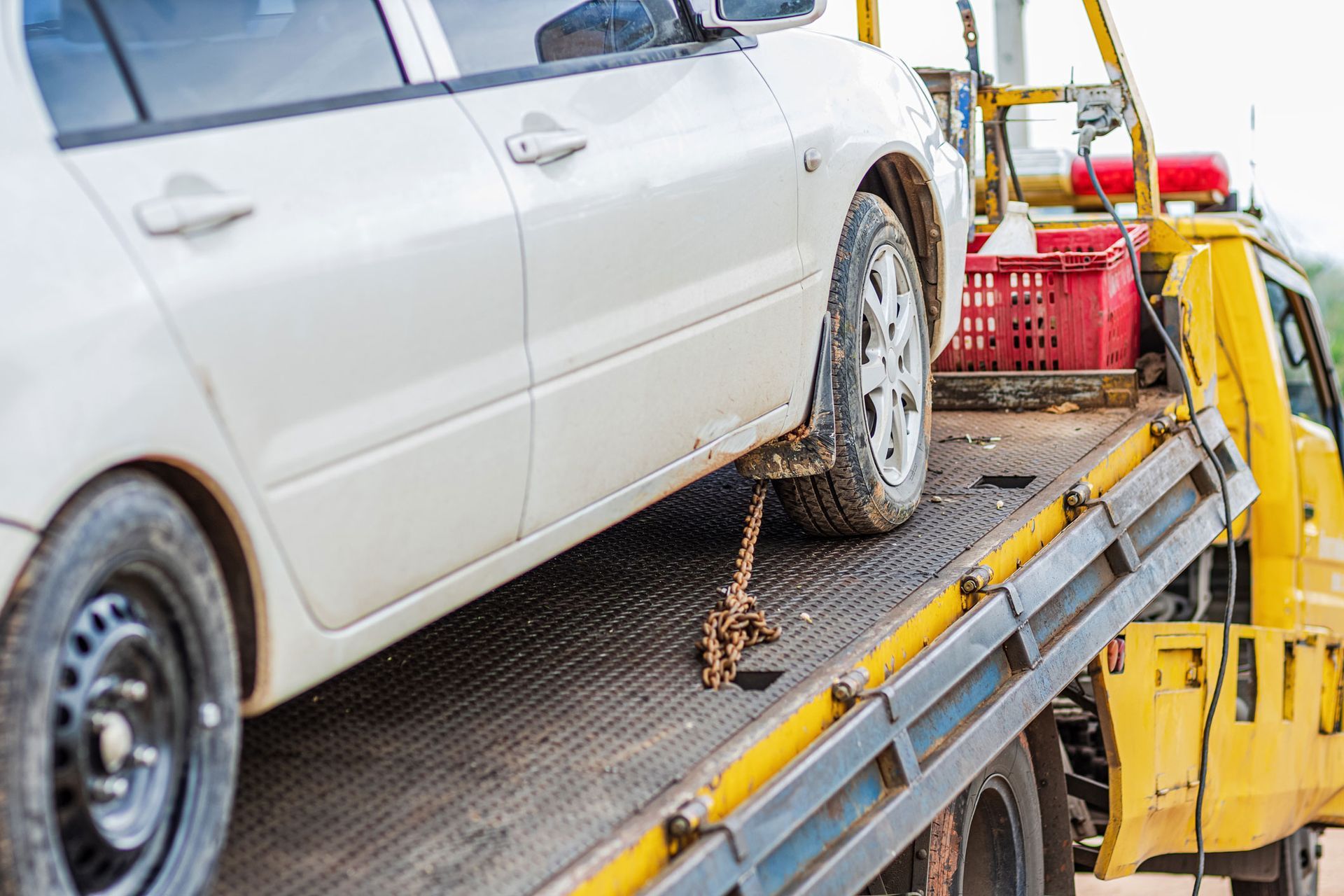 A white car is being towed by a tow truck.