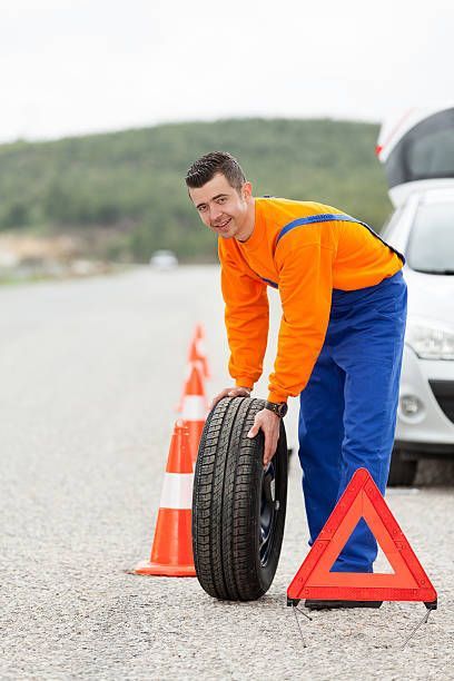 A man is changing a tire on the side of the road.