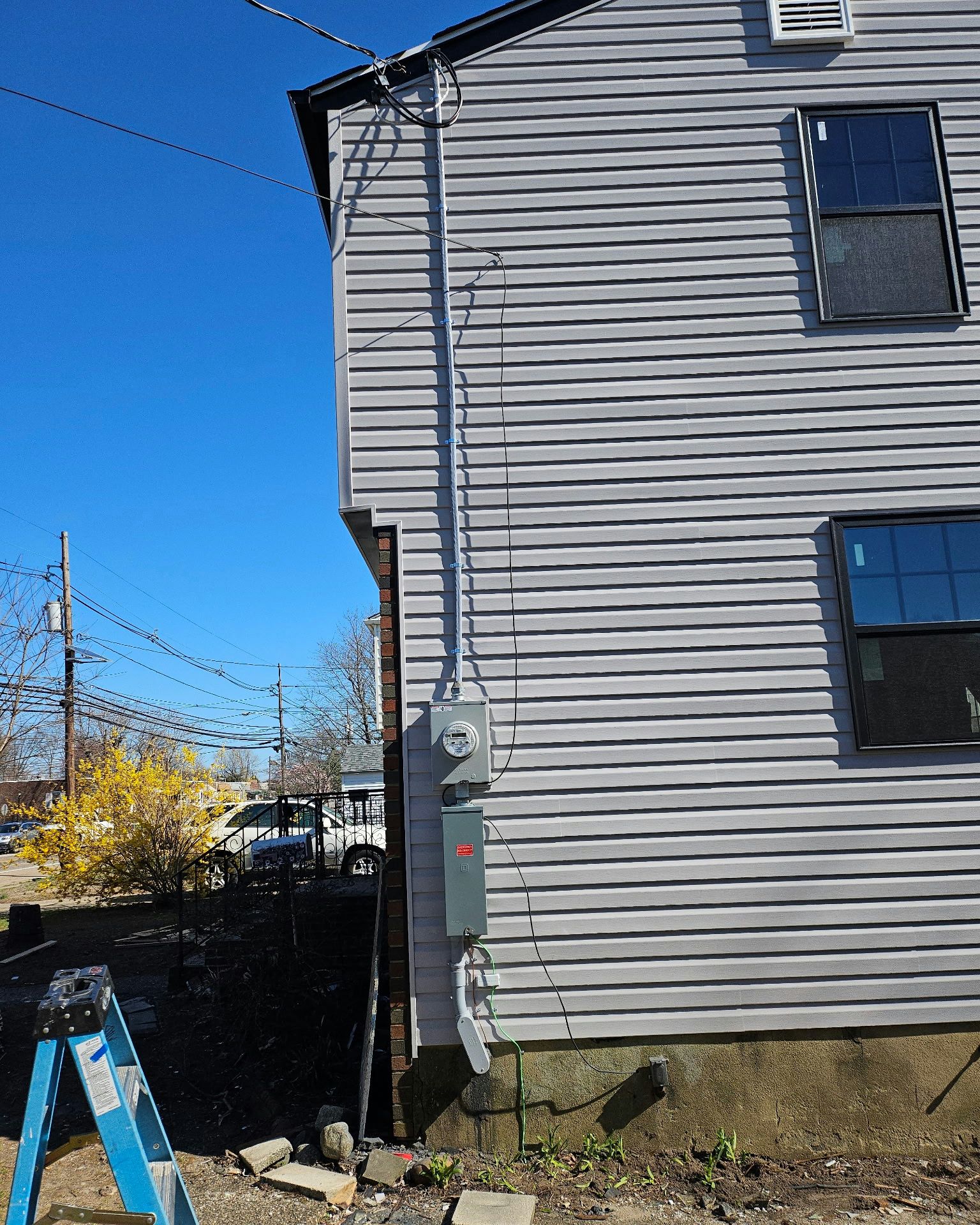 Electrical meter and conduit installed on the side of a gray-sided building under a blue sky.
