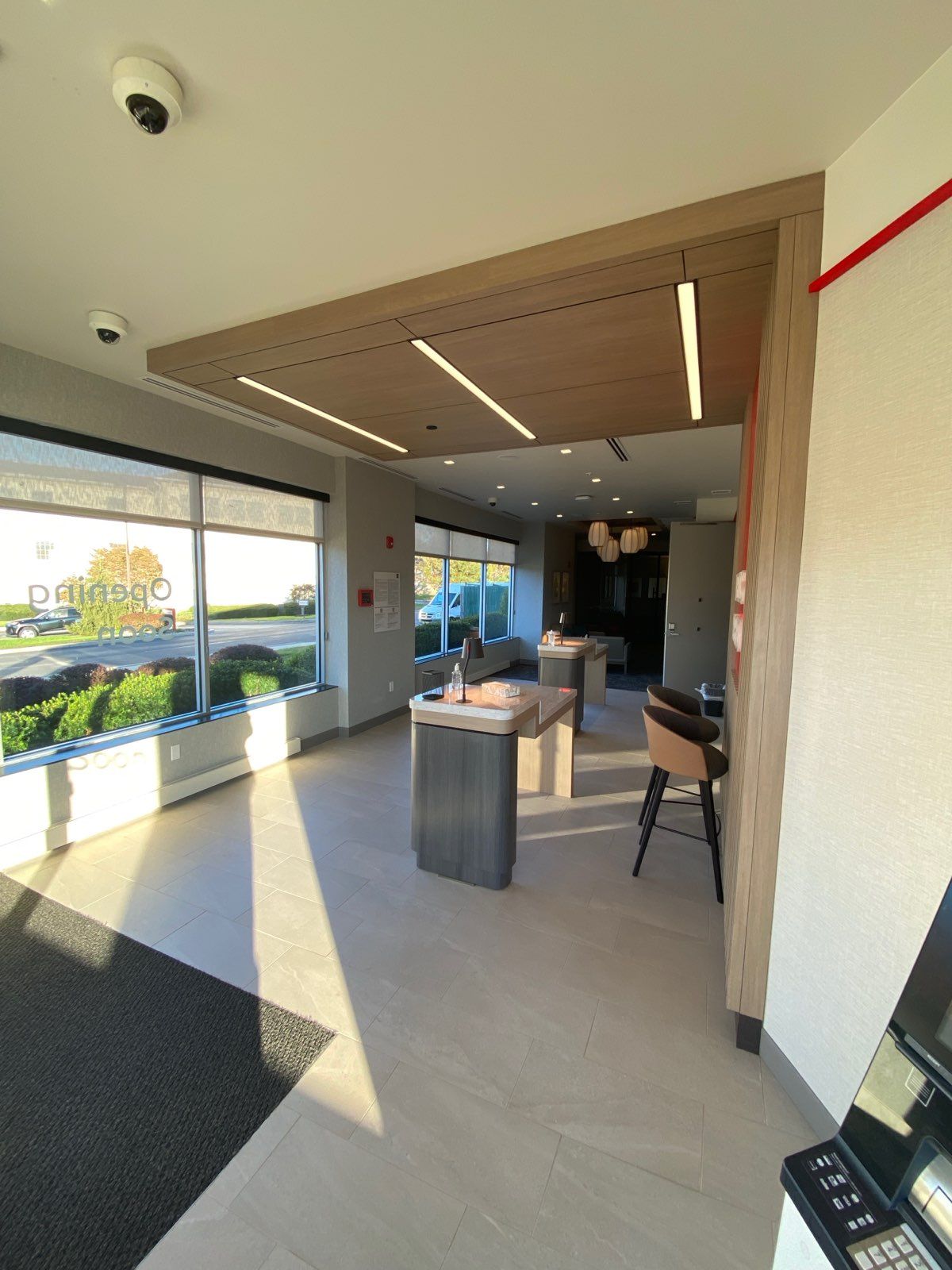 Interior of a bank lobby with seating, counters, and large windows. Neutral colors and modern design.