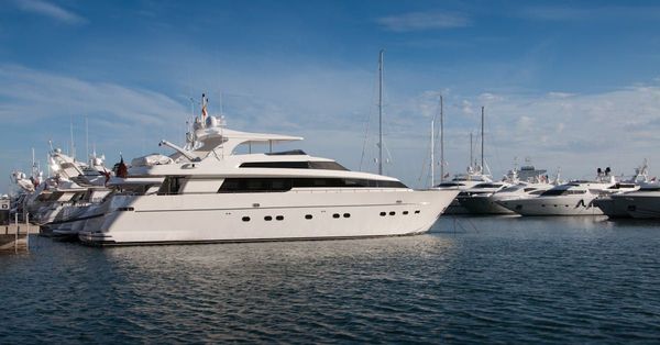 A large white yacht is docked in a marina.