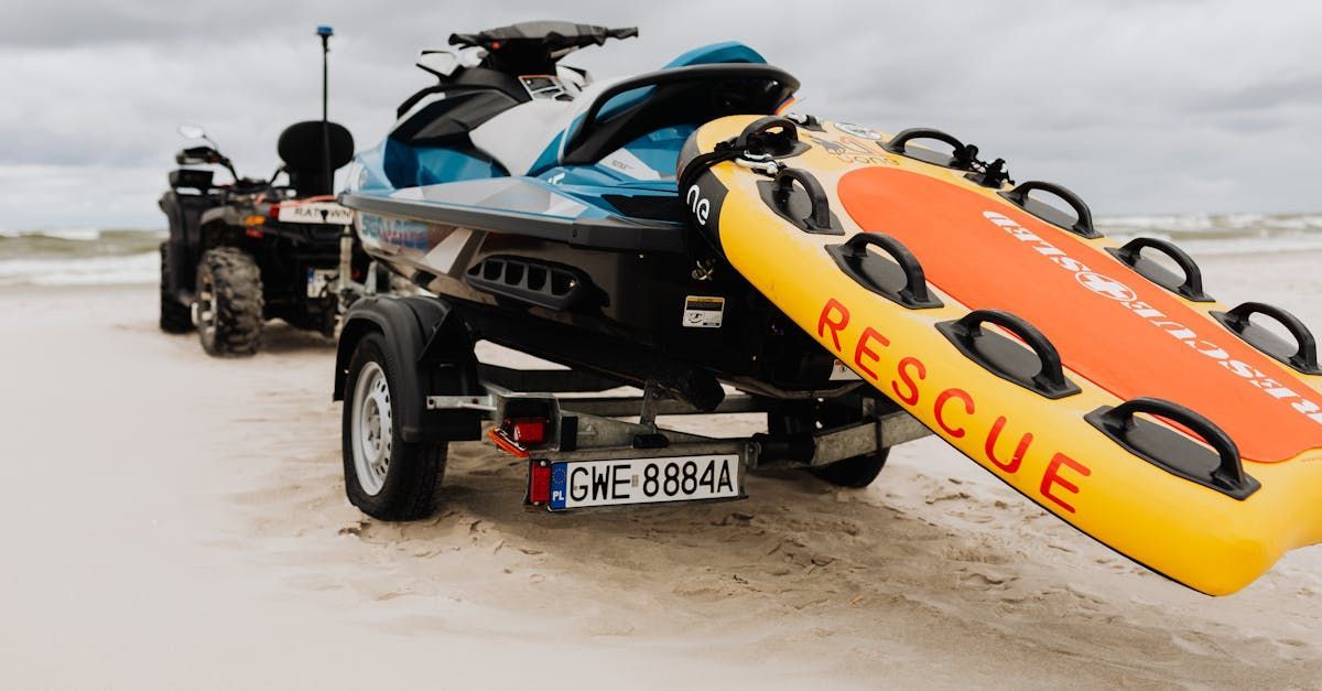 A jet ski is being towed by a trailer on the beach.