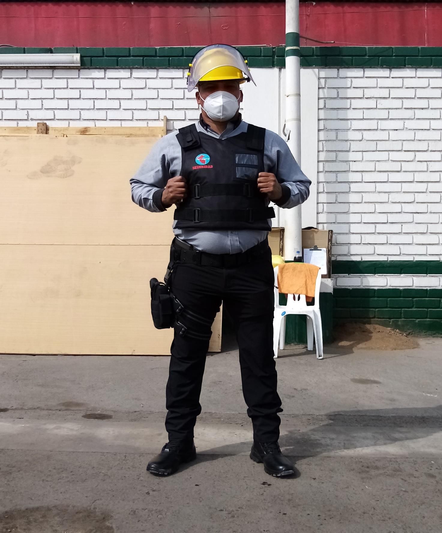 Persona uniformada, con casco, chaleco y mascarilla, de pie al aire libre.