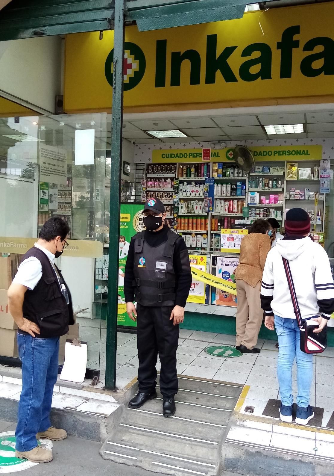 Gente afuera de una farmacia; un guardia de seguridad está en la entrada.