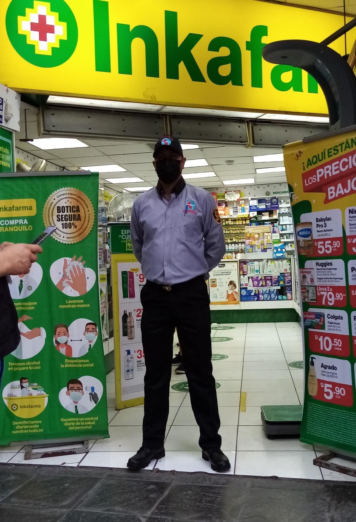 Un hombre uniformado se encuentra frente a la entrada de una farmacia. El cartel dice 