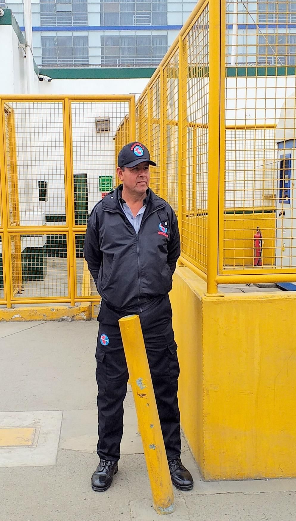 Un guardia de seguridad está de pie cerca de una puerta metálica amarilla
