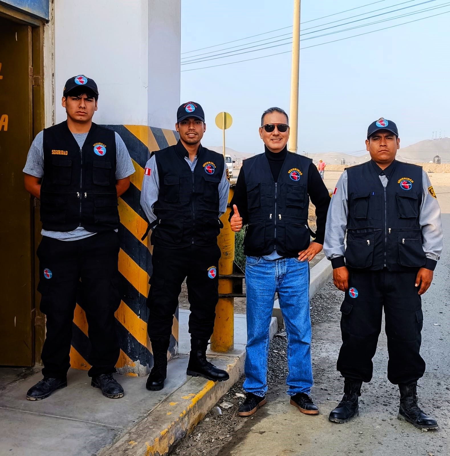 Cuatro personas uniformadas posando cerca de una cabina de peaje
